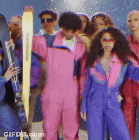 A Man In A Pink Suit Holds A Pair Of Skis GIF