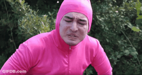 A Man In A Pink Suit Is Making A Funny Face With His Eyes Closed GIF