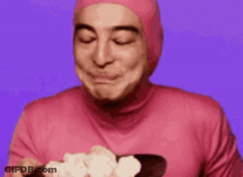 A Man In A Pink Suit Is Smiling And Making A Funny Face . GIF