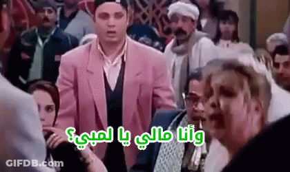A Man In A Pink Suit Is Standing In A Crowd Of People And Talking To A Woman . GIF