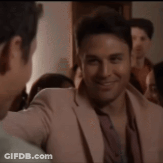 A Man In A Pink Suit Is Talking To Another Man In A Crowd GIF