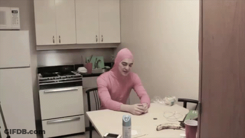 A Man In A Pink Suit Sits At A Table GIF
