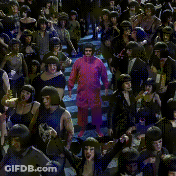 A Man In A Pink Suit Stands In The Middle Of A Crowd GIF