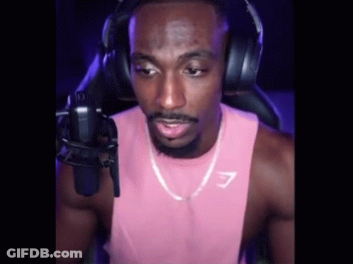 A Man In A Pink Tank Top And Headphones Is Talking Into A Microphone . GIF