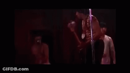 A Man In A Pink Tank Top And Sunglasses Is Playing A Guitar . GIF