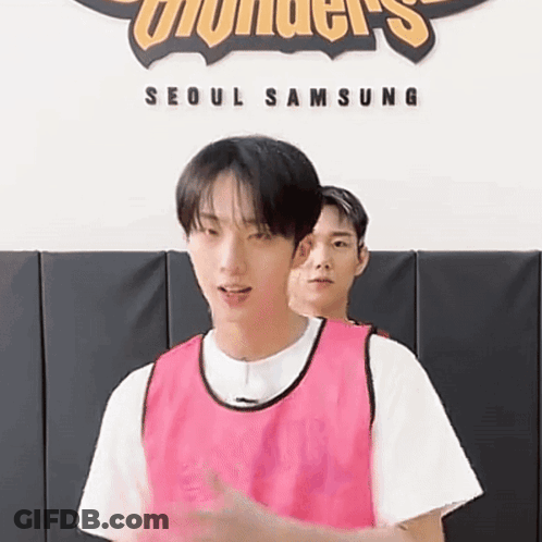 A Man In A Pink Vest Is Standing Next To Another Man In A White Shirt . GIF