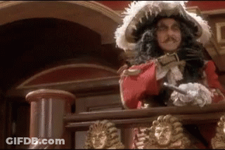 A Man In A Pirate Costume Is Standing On A Balcony With A Sword . GIF