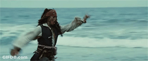 A Man In A Pirate Costume Is Standing On A Beach In Front Of The Ocean . GIF