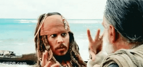 A Man In A Pirate Costume Is Talking To Another Man In Front Of The Ocean . GIF
