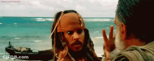 A Man In A Pirate Outfit Is Talking To Another Man On The Beach . GIF