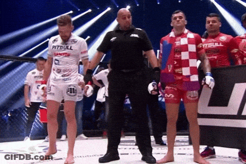 A Man In A Pitbull Shirt Stands Next To A Referee GIF