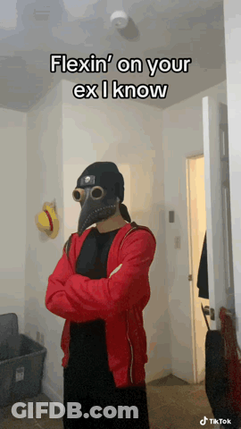 A Man In A Plague Doctor Mask Is Standing In A Hallway With His Arms Crossed GIF