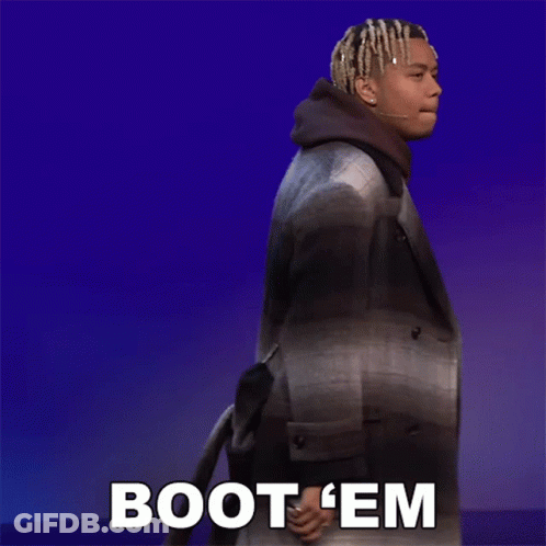 A Man In A Plaid Coat Is Walking With The Words Boot 'Em Behind Him GIF