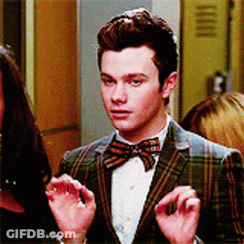 A Man In A Plaid Jacket And Bow Tie Is Talking To A Woman GIF