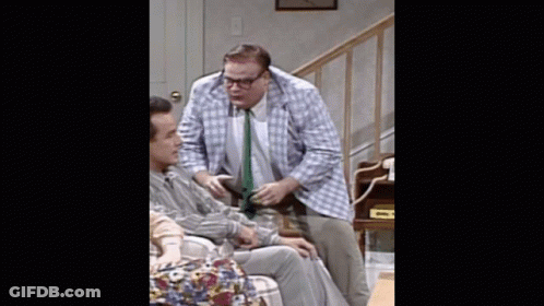 A Man In A Plaid Jacket And Tie Is Talking To Another Man In A Chair GIF