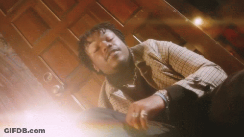 A Man In A Plaid Jacket Is Laying Down In Front Of A Wooden Door . GIF