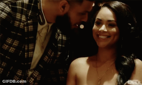 A Man In A Plaid Jacket Kisses A Smiling Woman On The Forehead GIF