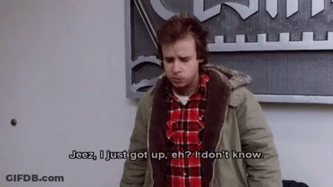 A Man In A Plaid Shirt And A Jacket Is Standing In Front Of A Wall . GIF