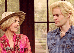A Man In A Plaid Shirt And A Woman In A Cowboy Hat Are Looking At Each Other GIF