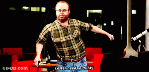 A Man In A Plaid Shirt And Jeans Says Lester Needs A Drink GIF