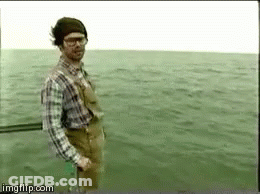 A Man In A Plaid Shirt And Overalls Is Standing In The Water . GIF