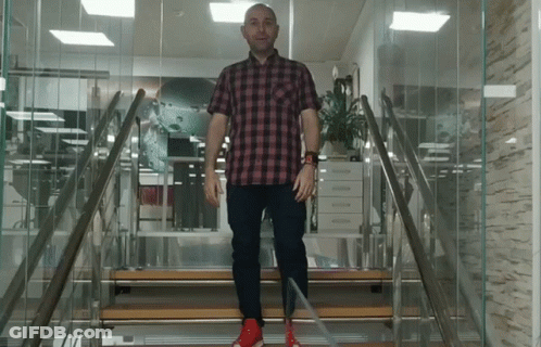 A Man In A Plaid Shirt And Red Shoes Is Walking Up A Set Of Stairs GIF
