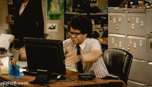 A Man In A Plaid Shirt And Tie Is Sitting At A Desk In Front Of A Computer GIF