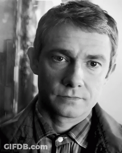 A Man In A Plaid Shirt And Tie Looks At The Camera In A Black And White Photo . GIF