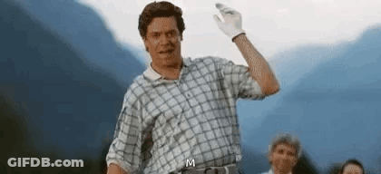 A Man In A Plaid Shirt And White Gloves Is Waving His Hand In Front Of Mountains . GIF
