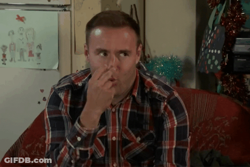 A Man In A Plaid Shirt Holds His Nose GIF