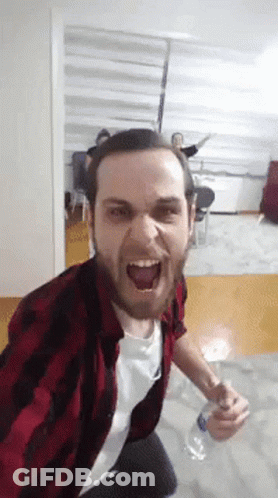 A Man In A Plaid Shirt Is Holding A Bottle Of Water GIF