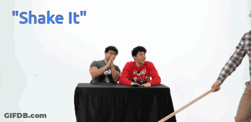 A Man In A Plaid Shirt Is Holding A Cane In Front Of A Chalkboard That Says Shake It GIF