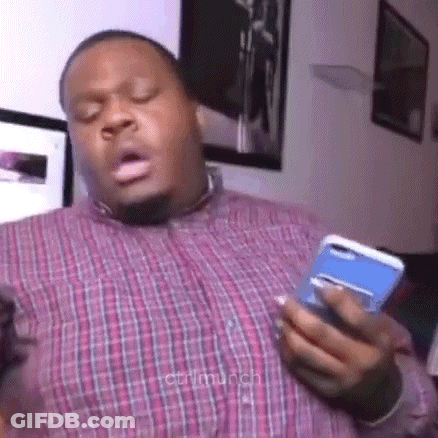 A Man In A Plaid Shirt Is Holding A Cell Phone In His Hand And Making A Funny Face . GIF