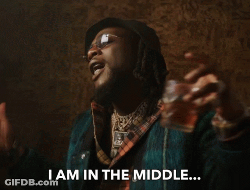 A Man In A Plaid Shirt Is Holding A Glass And Says " I Am In The Middle " GIF