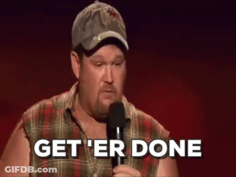 A Man In A Plaid Shirt Is Holding A Microphone And Says `` Get 'Er Done '' . GIF