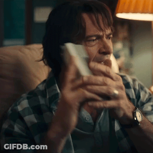A Man In A Plaid Shirt Is Holding A Piece Of Paper In His Hand GIF