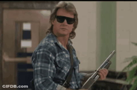 A Man In A Plaid Shirt Is Holding A Shotgun GIF