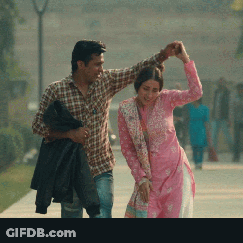 A Man In A Plaid Shirt Is Holding A Woman In A Pink Dress GIF