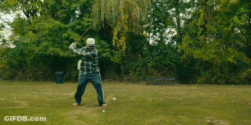 A Man In A Plaid Shirt Is Jumping In The Air In A Park GIF