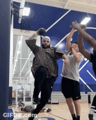 A Man In A Plaid Shirt Is Jumping In The Air With A Basketball In His Hand GIF
