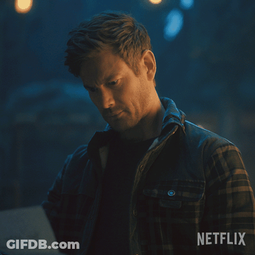 A Man In A Plaid Shirt Is Looking At A Piece Of Paper With Netflix Written On The Bottom GIF