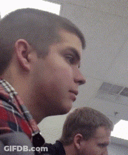 A Man In A Plaid Shirt Is Looking To His Left GIF