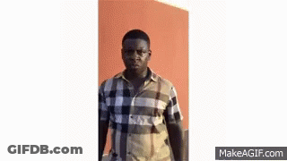 A Man In A Plaid Shirt Is Making A Funny Face And Looking At The Camera . GIF