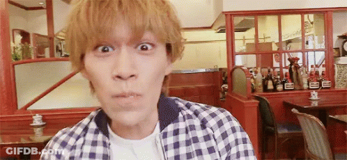 A Man In A Plaid Shirt Is Making A Funny Face In Front Of A Restaurant . GIF