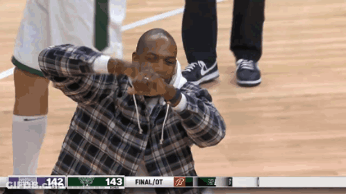 A Man In A Plaid Shirt Is Making A Funny Face In Front Of A Scoreboard That Says 143 Final / Ot GIF