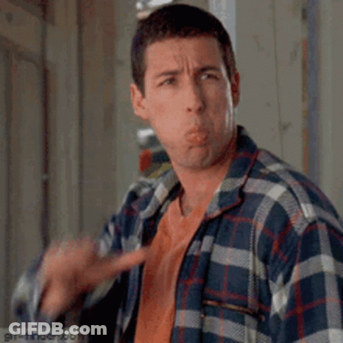 A Man In A Plaid Shirt Is Making A Funny Face While Pointing At The Camera . GIF