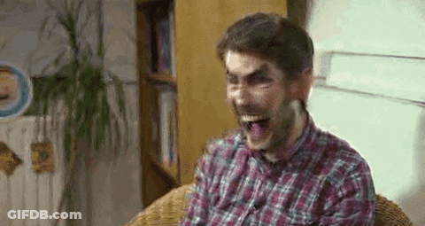 A Man In A Plaid Shirt Is Making A Funny Face While Sitting In A Chair . GIF