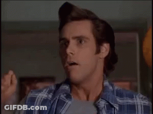 A Man In A Plaid Shirt Is Making A Funny Face While Standing In A Room . GIF