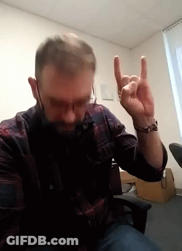 A Man In A Plaid Shirt Is Making A Horns Sign With His Fingers GIF