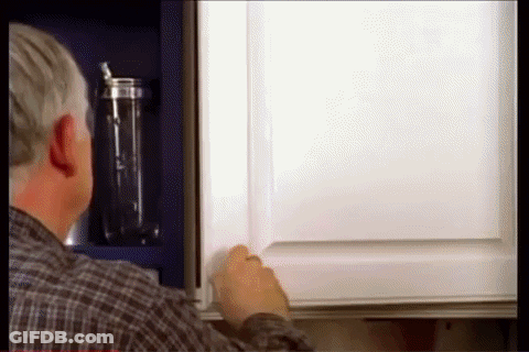 A Man In A Plaid Shirt Is Opening A Cabinet GIF